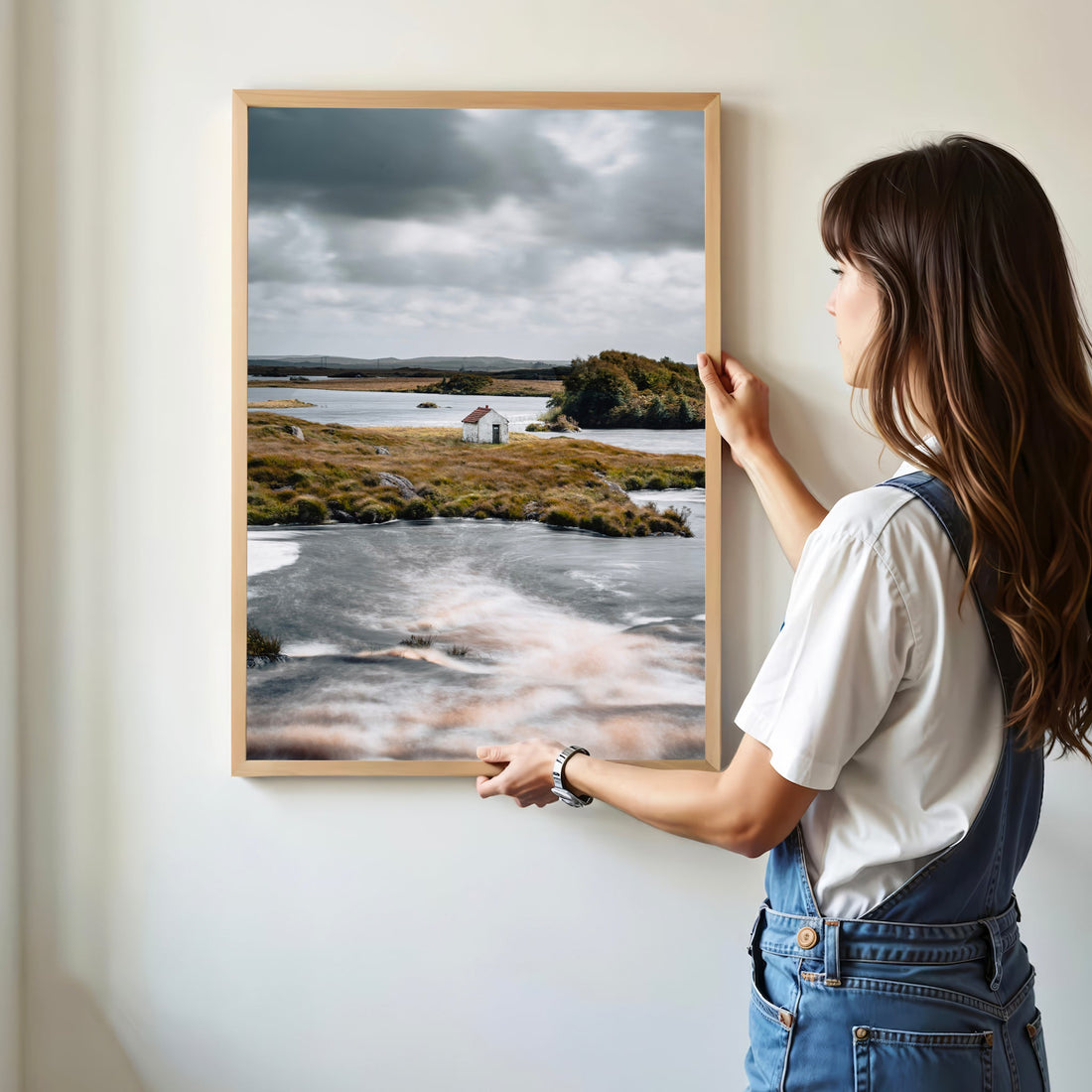 Woman hanging Connemara wall art print featuring a remote Irish hut