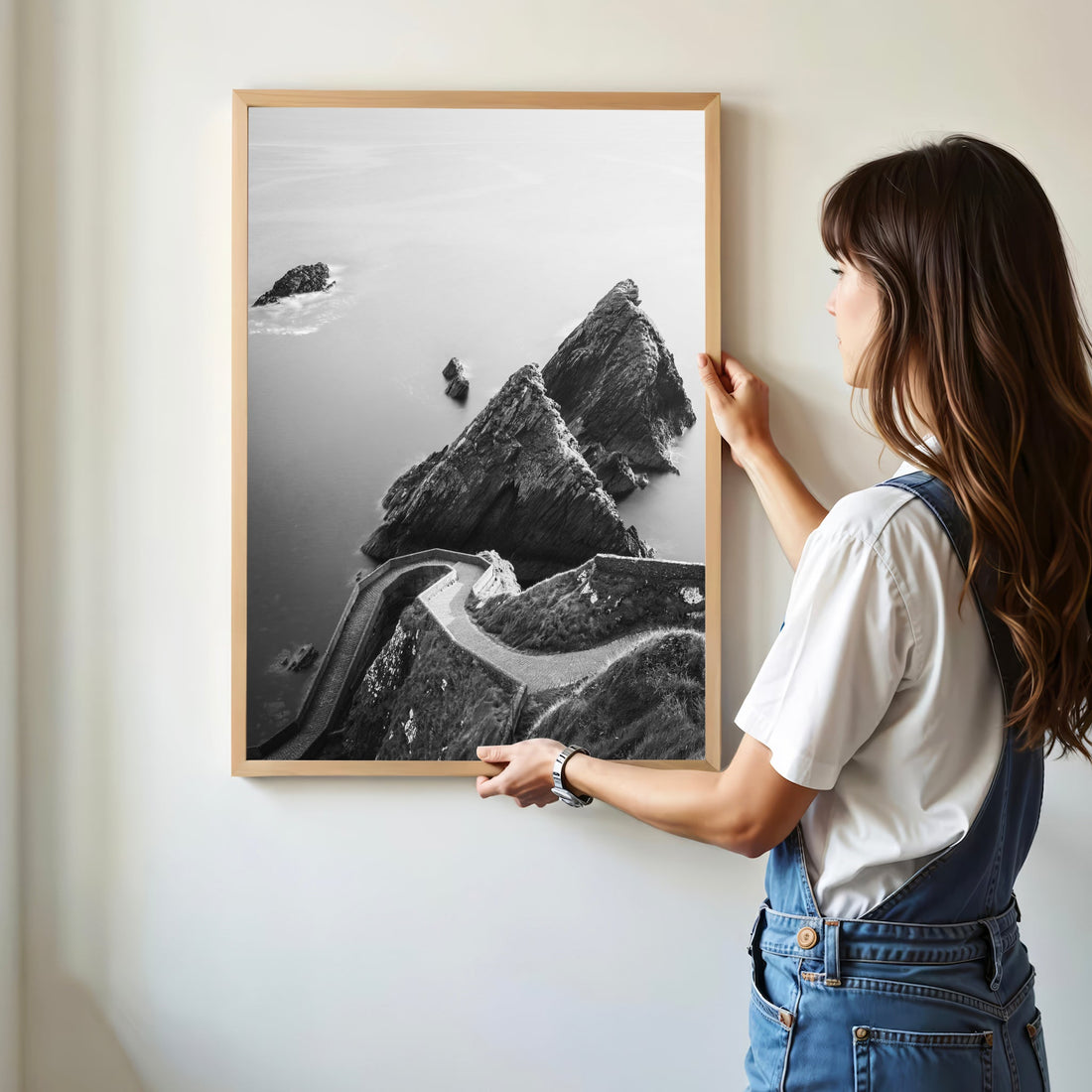 Woman hanging a Dunquin Pier print on a wall