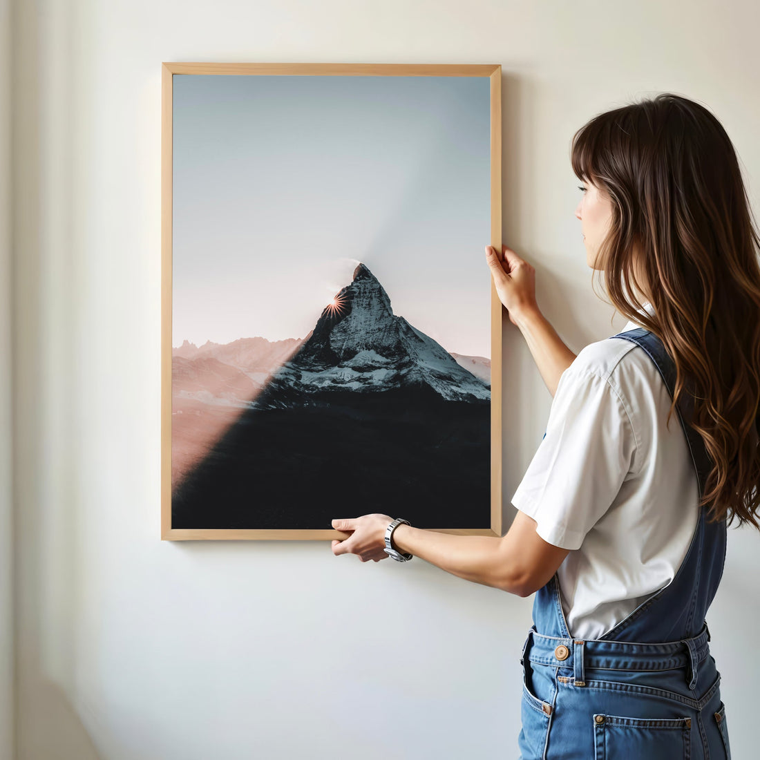 Woman placing Matterhorn sunset art print on a white wall in modern home