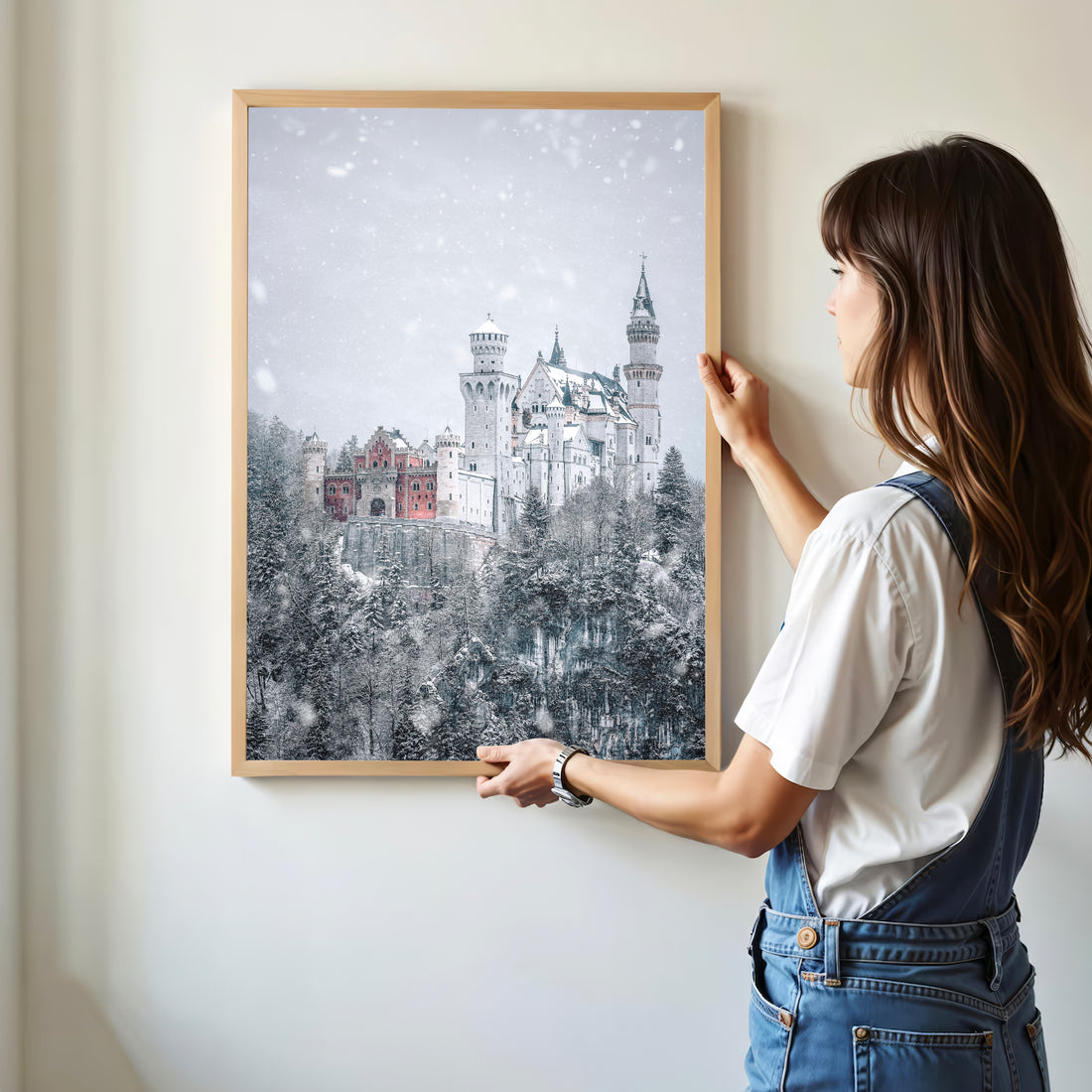 Woman hanging framed Neuschwanstein Castle winter print on a wall