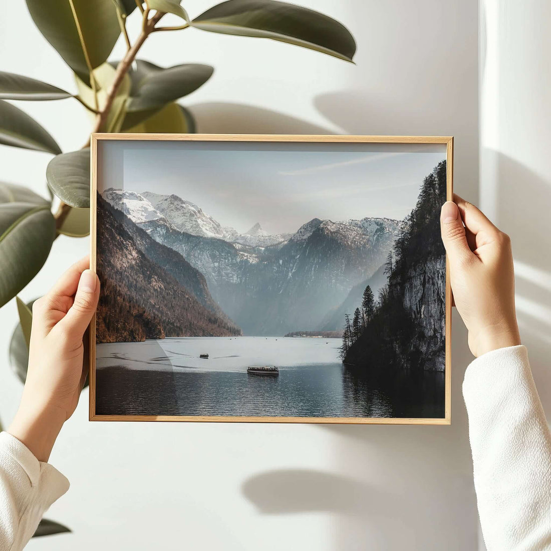 Woman holding framed Königssee lake print with mountain peaks and boat