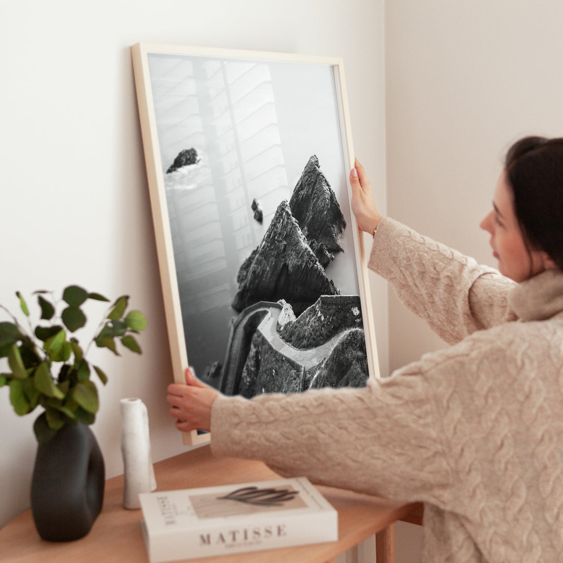 Woman placing Dunquin Pier print on wooden table beside plant