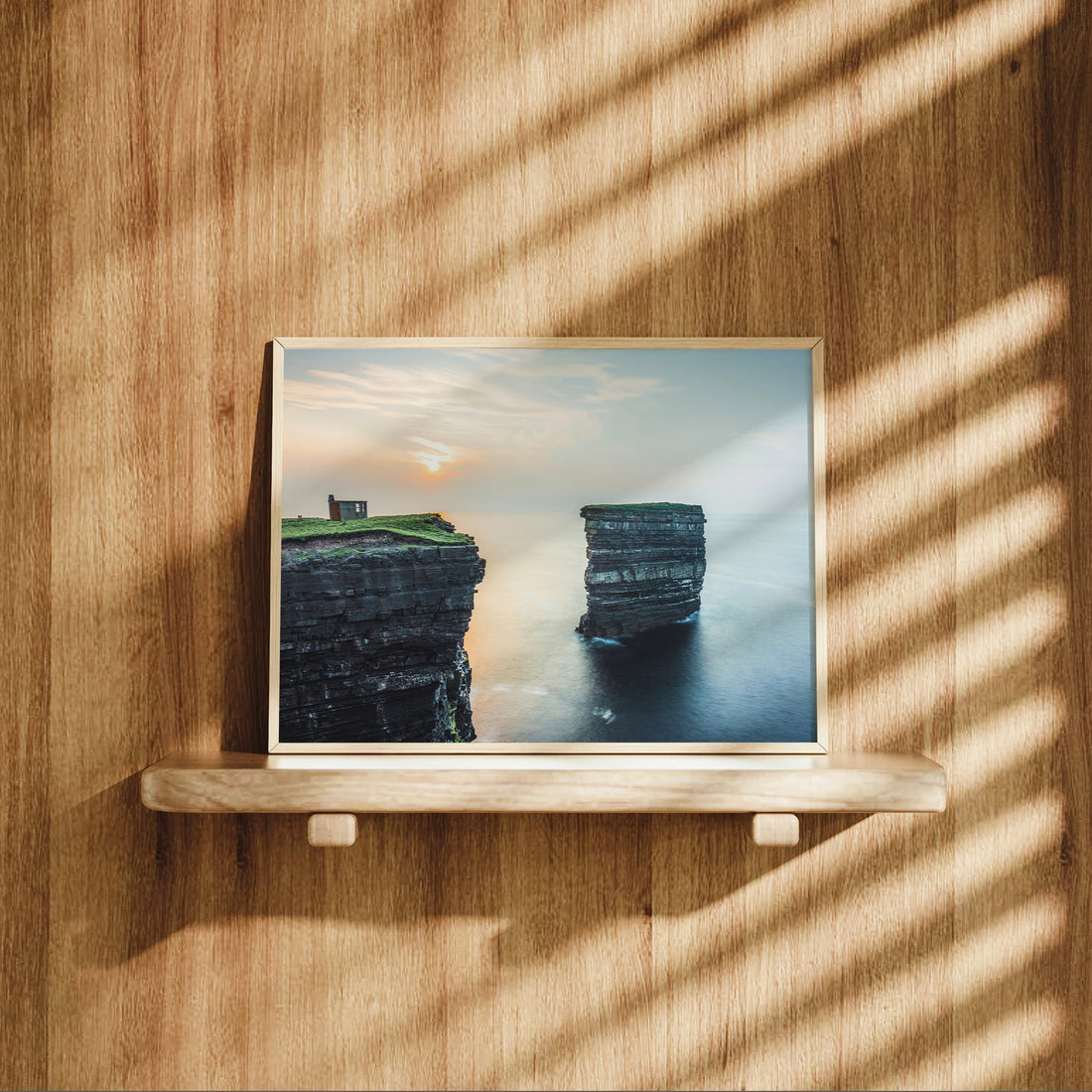 Downpatrick Head coastal print on wooden shelf with soft natural light and golden tones