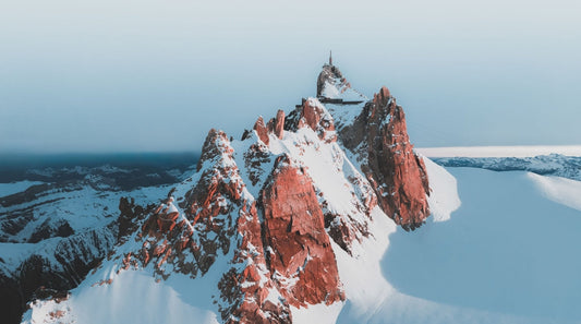 A snowy view onto the Cosmiques Traverse in Chamonix Mont Blanc, with clear and wintery views of the Aiguille du Midi cable car station.