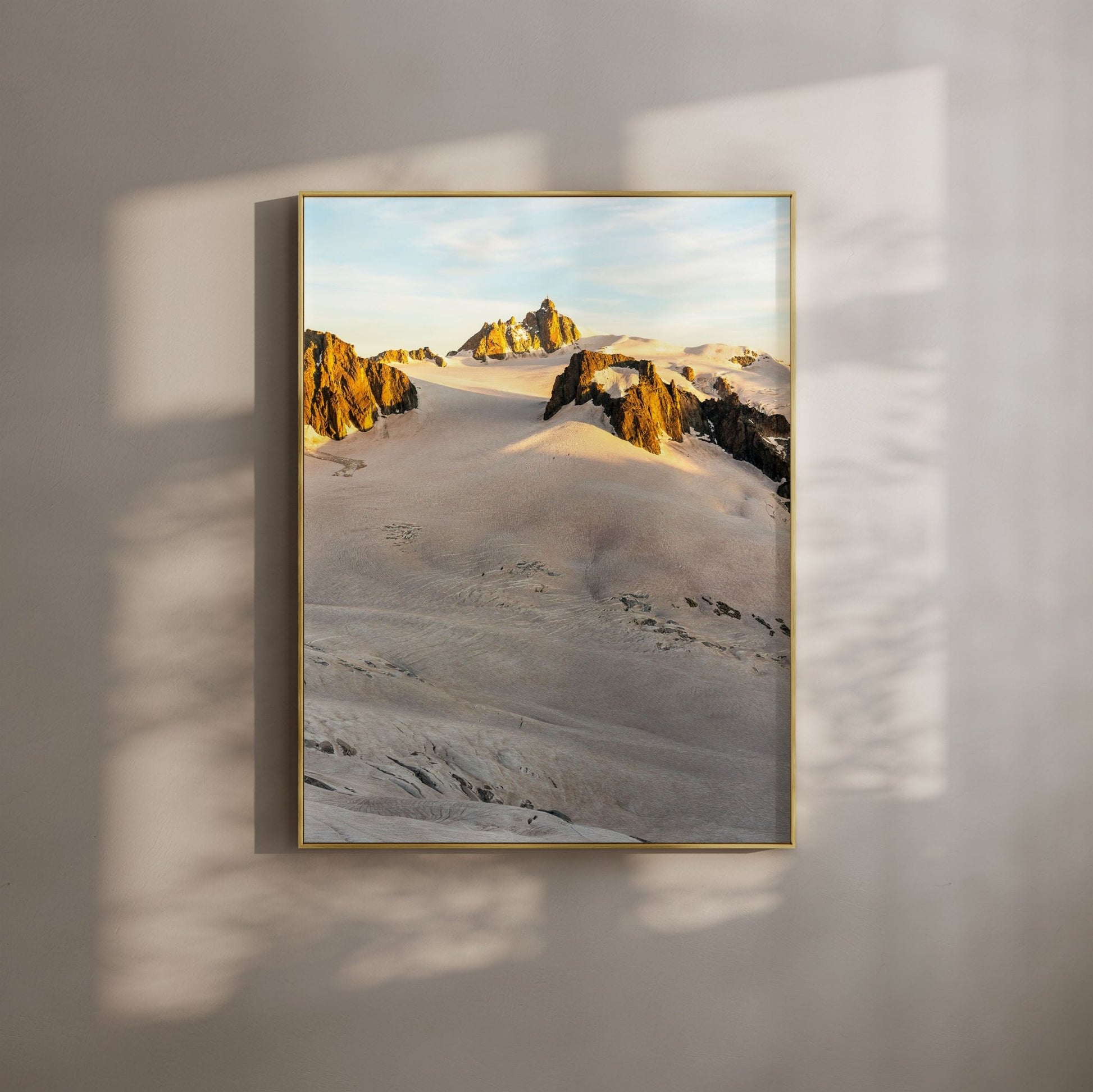 Aiguille du Midi illuminated with soft alpenglow at sunset, framed by jagged alpine ridges.