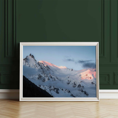 Framed wall art of the Aiguille du Midi with alpenglow at dawn, leaning against a deep green wall.