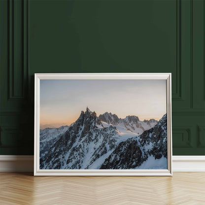 Framed Chamonix mountain print of the Aiguille du Midi at sunset, leaning against a green wall.