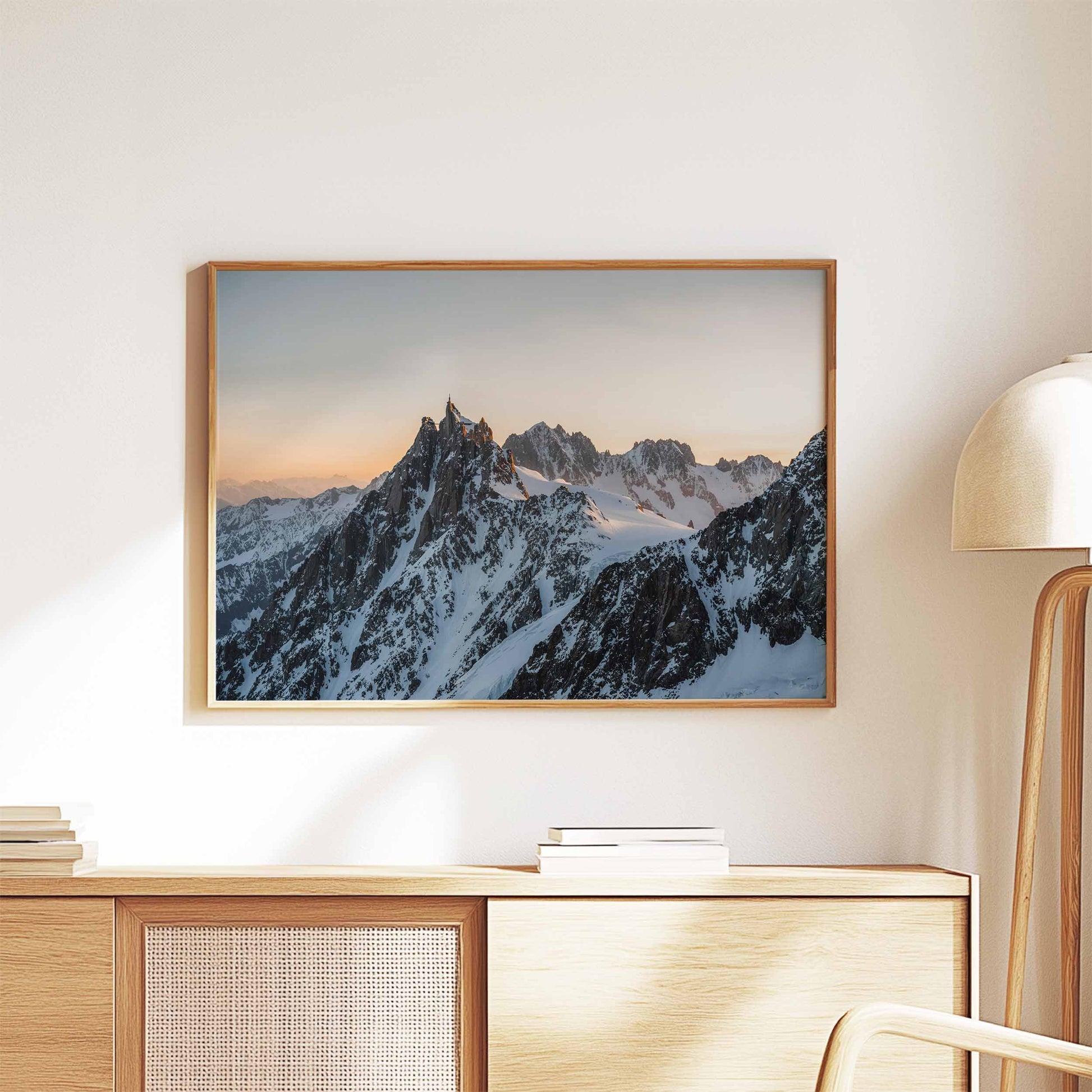 Wall art of the Aiguille du Midi at sunset, beautifully framed and styled on a wooden cabinet.