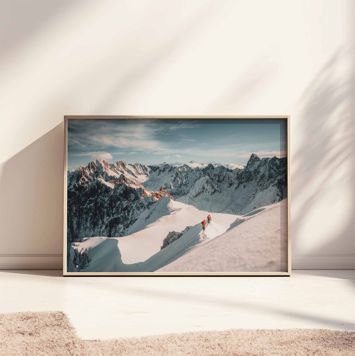 Large framed wall art print of two climbers on a snowy ridge with dramatic alpine peaks, styled on the floor.