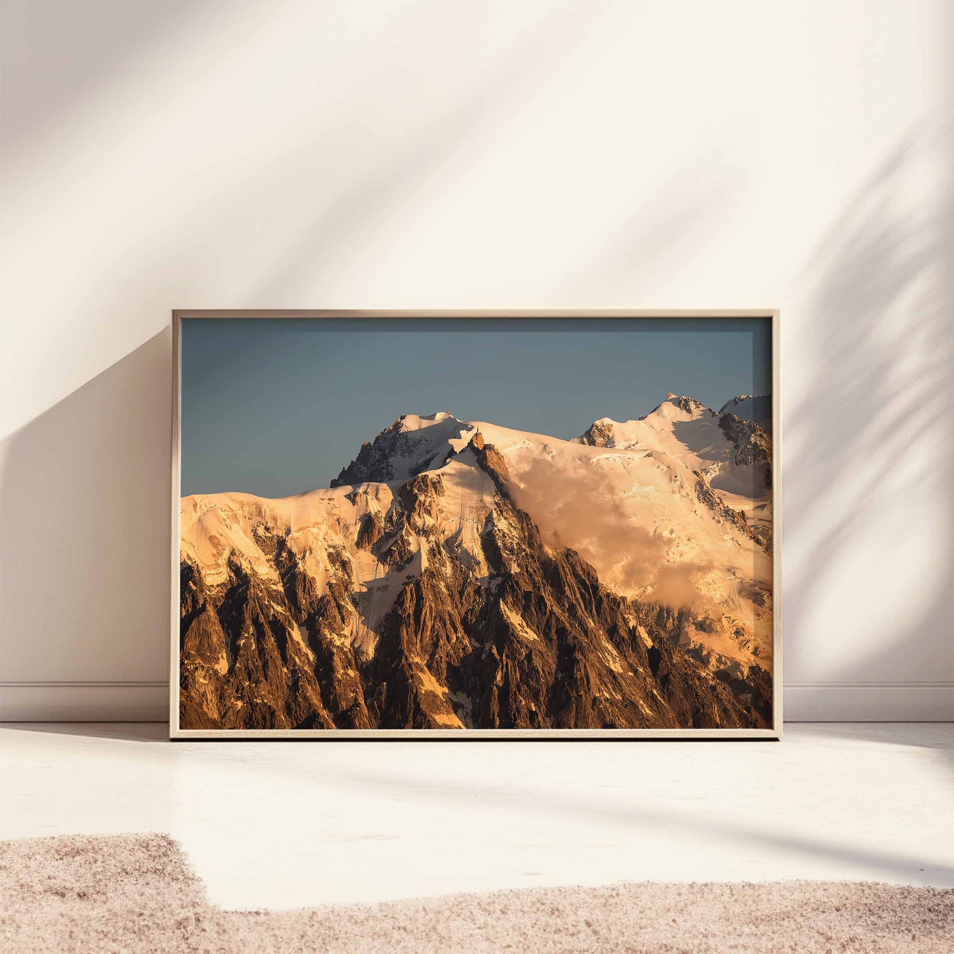 Large framed Aiguille du Midi sunset print styled on a sunlit floor with minimalist decor.