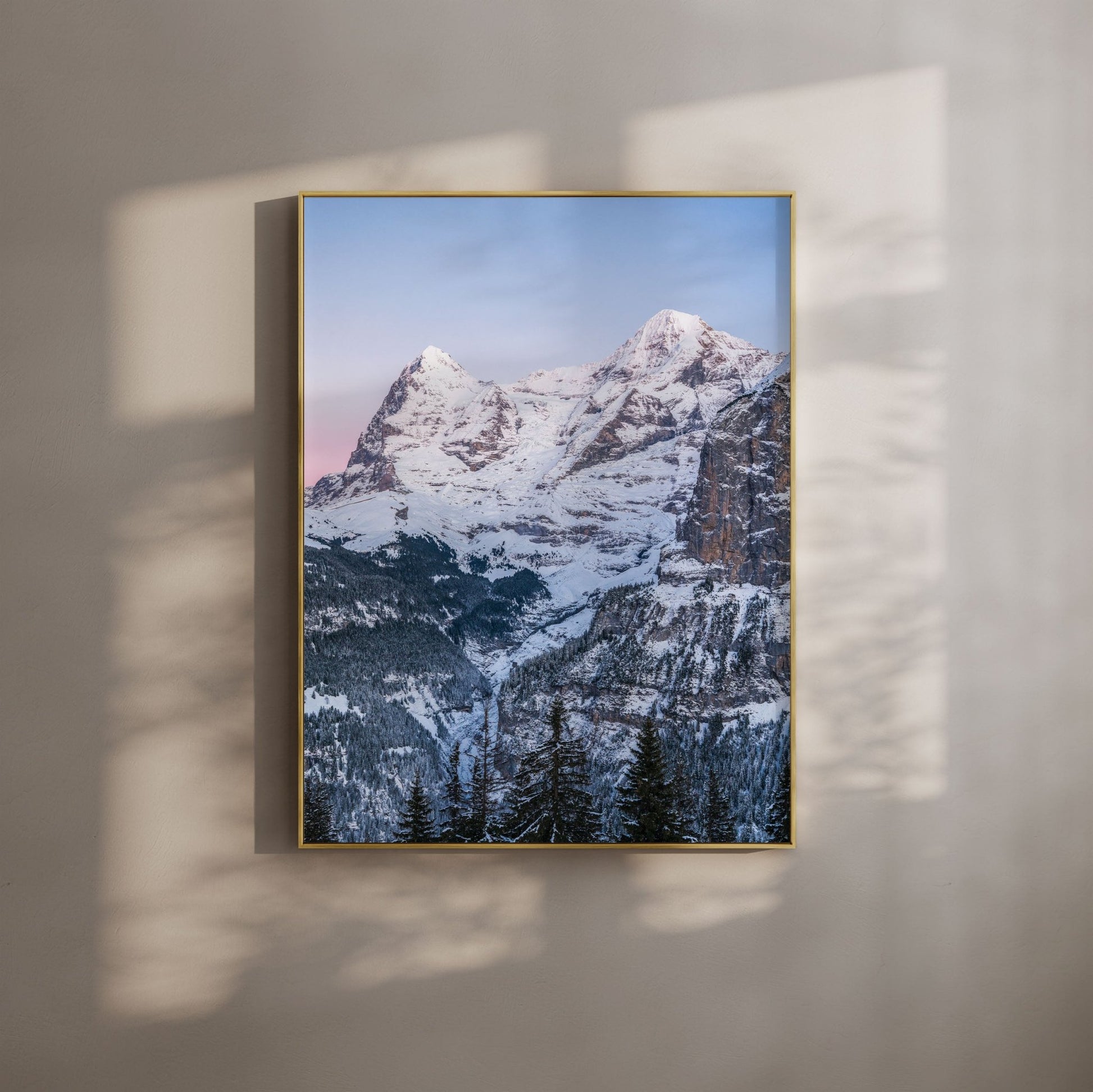 Golden hour view of Eiger and Mönch peaks in the Swiss Alps with a snowy foreground.