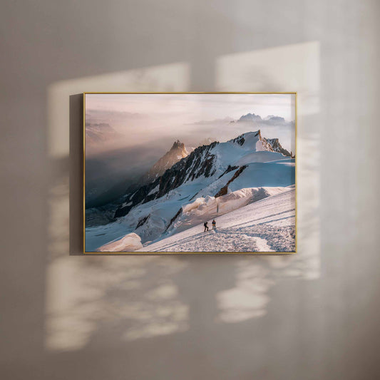 Two mountaineers climbing Mont Blanc at sunrise, with snow-covered peaks in the background.