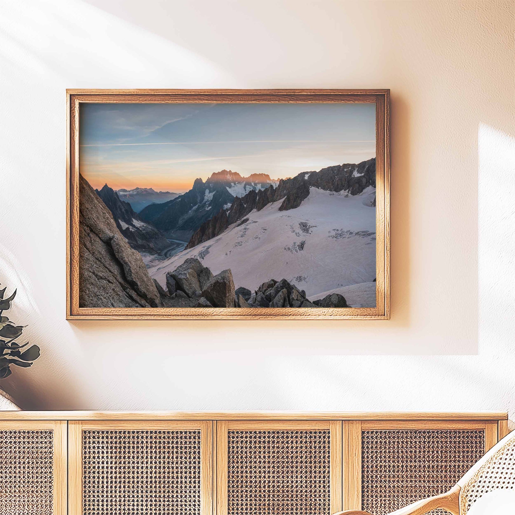 Sunset view of Mer de Glace glacier in a wooden frame, displayed on a modern console.