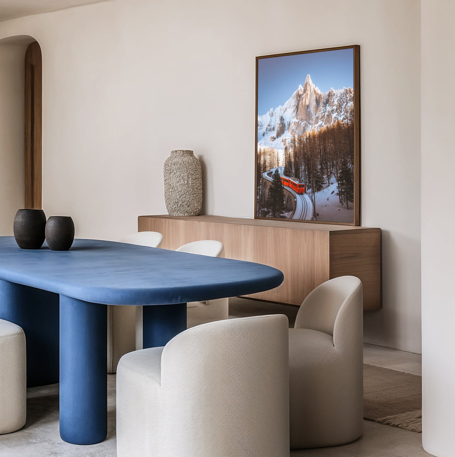 A ChamonixPrints image of the Drus and the Chamonix Montenverse train in bright red with a blue sky, matching the modern decor of a dining room with a blue table.