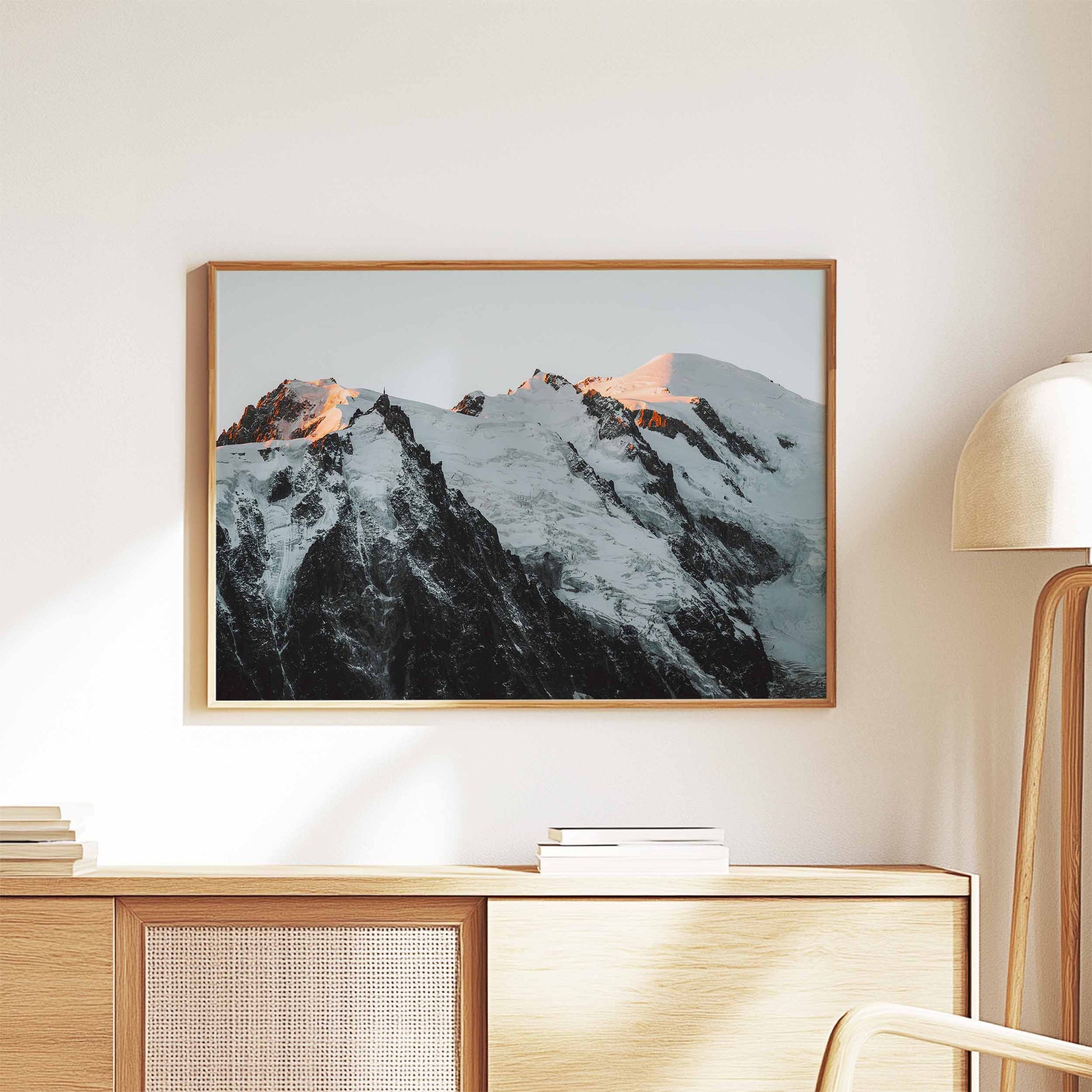 Elegant wall art of the Mont Blanc massif bathed in evening light, framed and styled on a wooden cabinet.