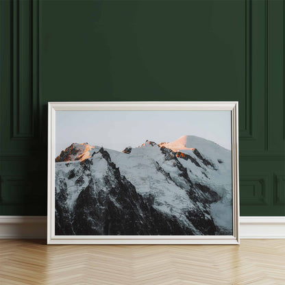 Framed print of the Mont Blanc massif glowing at sunset, leaning against a dark green wall.