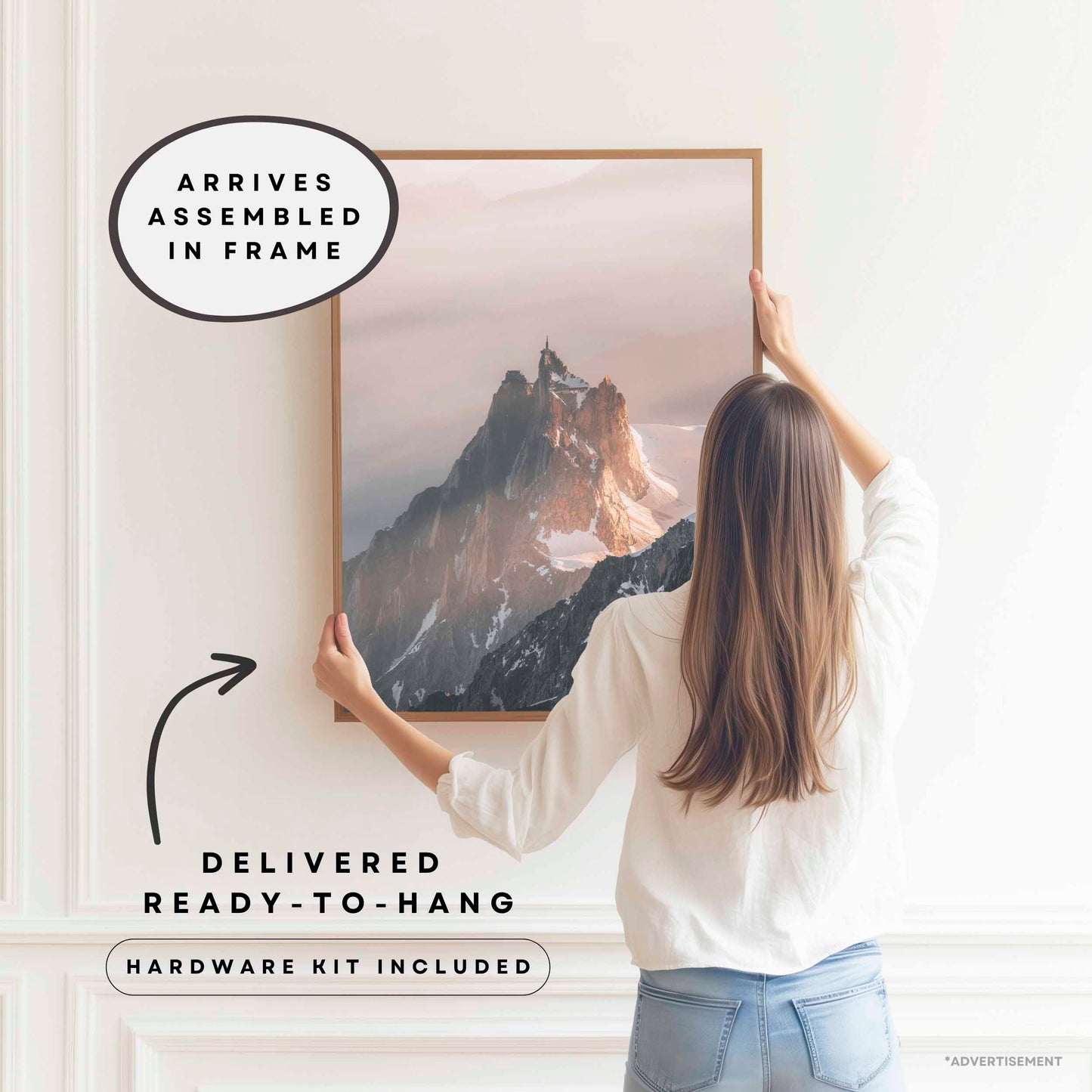 Premium ready-to-hang wall art featuring a framed photography print from Chamonix, France, displayed by a woman in a white interior, emphasizing convenience with hardware included and assembly complete.