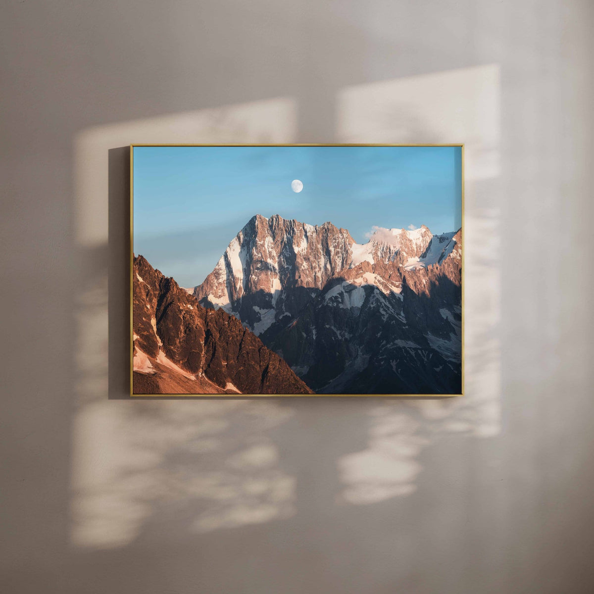 Grandes Jorasses wall art print with moon in sky, shown in a white-walled room with natural light