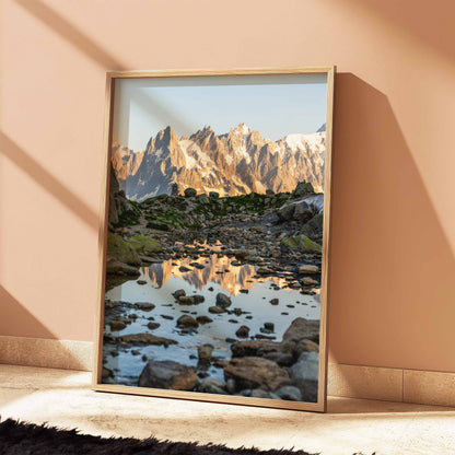 Dawn light illuminates the Aiguille de Chamonix with its reflection framed by alpine rocks.