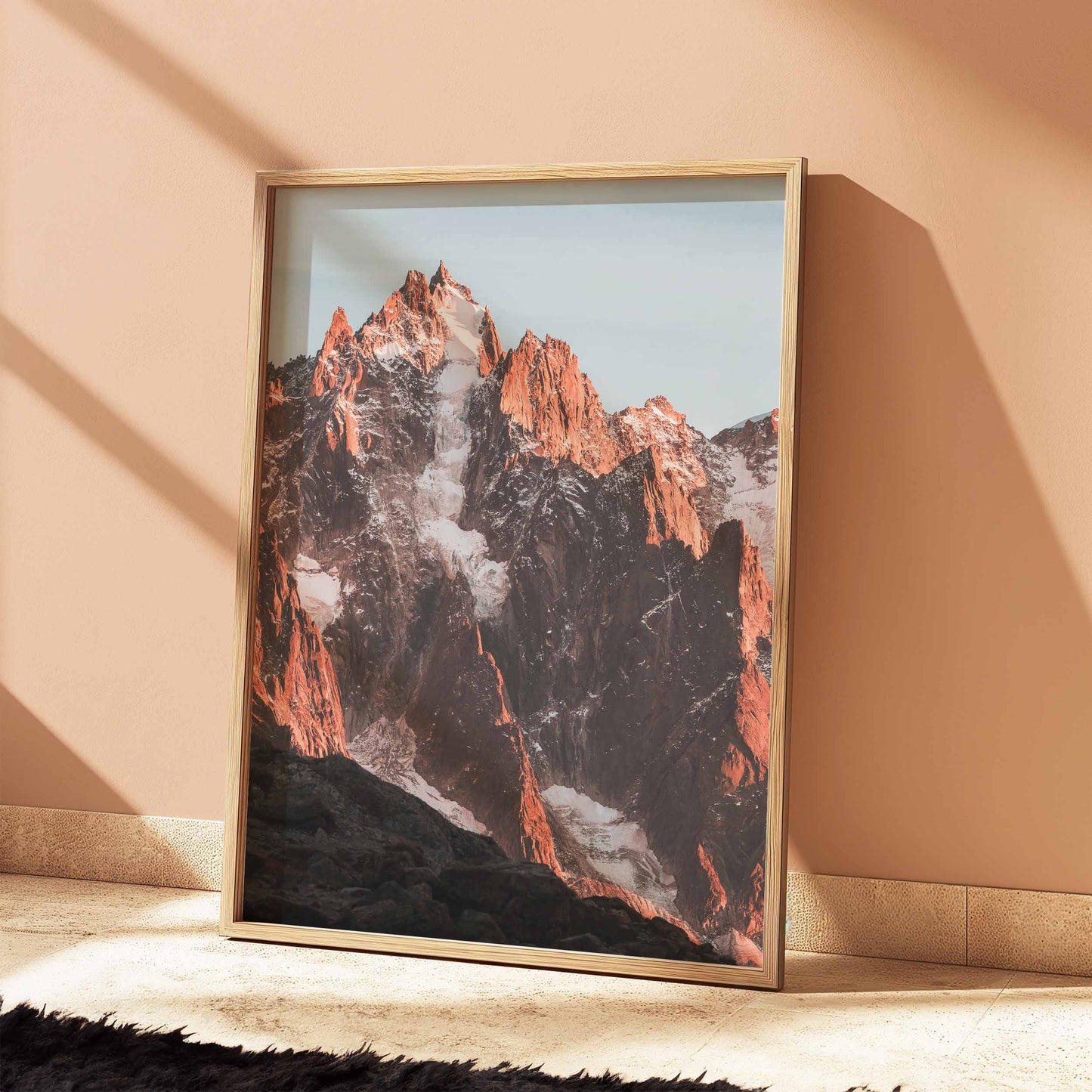 Iconic Aiguille de Chamonix peak bathed in sunset light, resting against a muted peach interior.