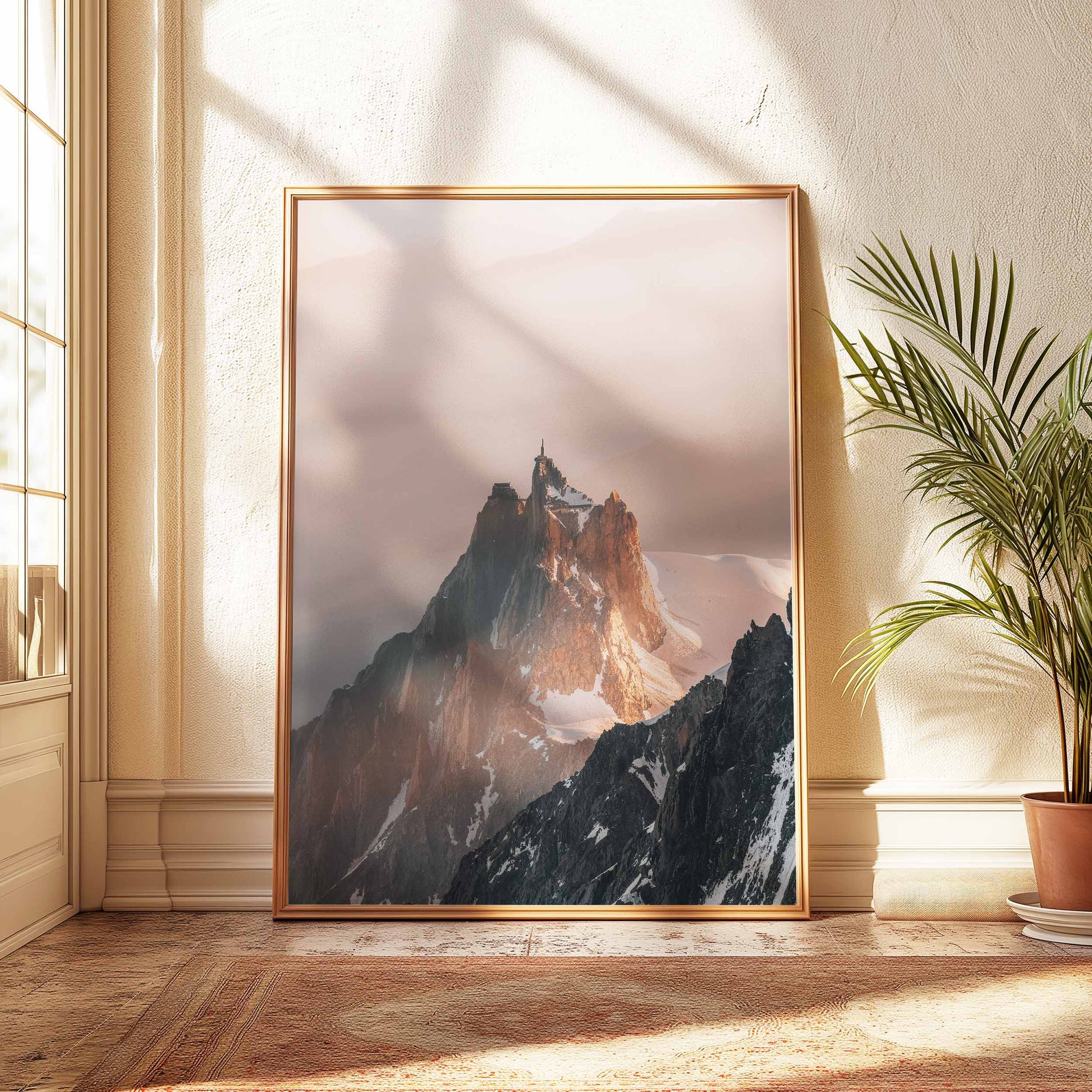 A golden wood frame showcasing Aiguille du Midi artwork in a sunlit room with rustic decor elements.