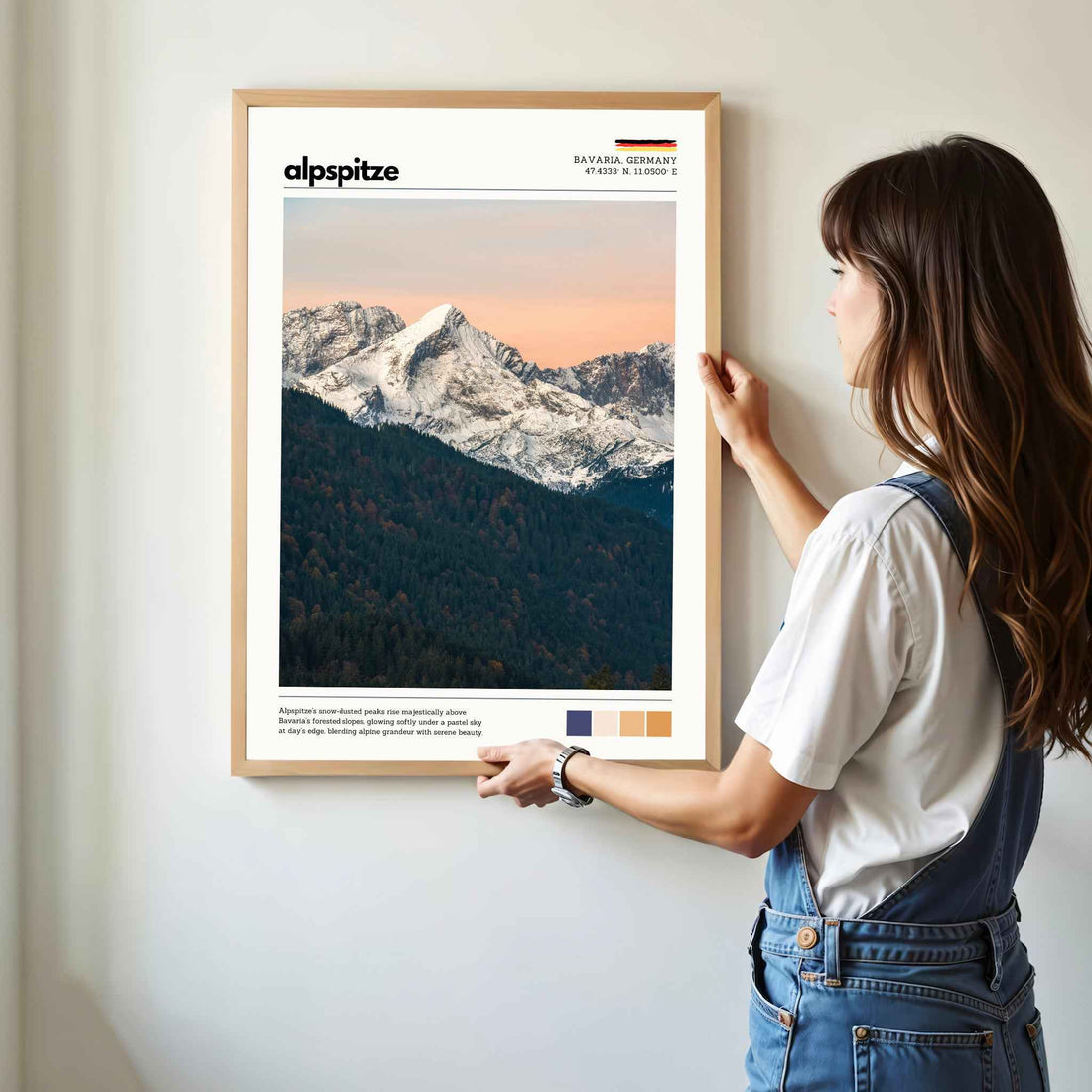Woman hanging framed Alpspitze Bavaria Germany photography print in natural oak frame on white wall