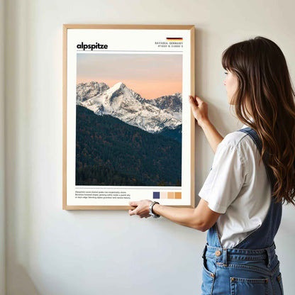 Woman hanging framed Alpspitze Bavaria Germany photography print in natural oak frame on white wall