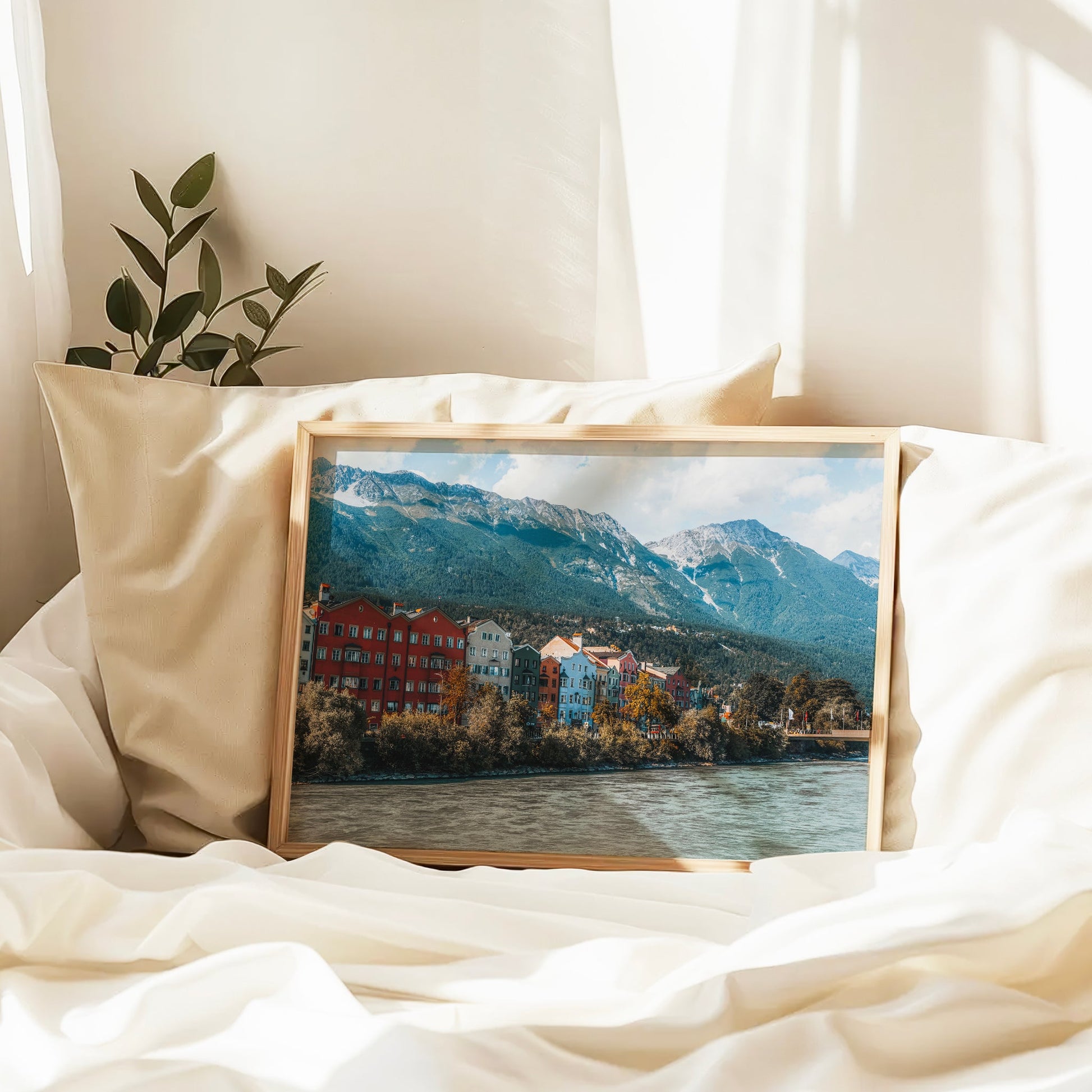 Innsbruck cityscape art displayed in a modern home with houseplants and books.