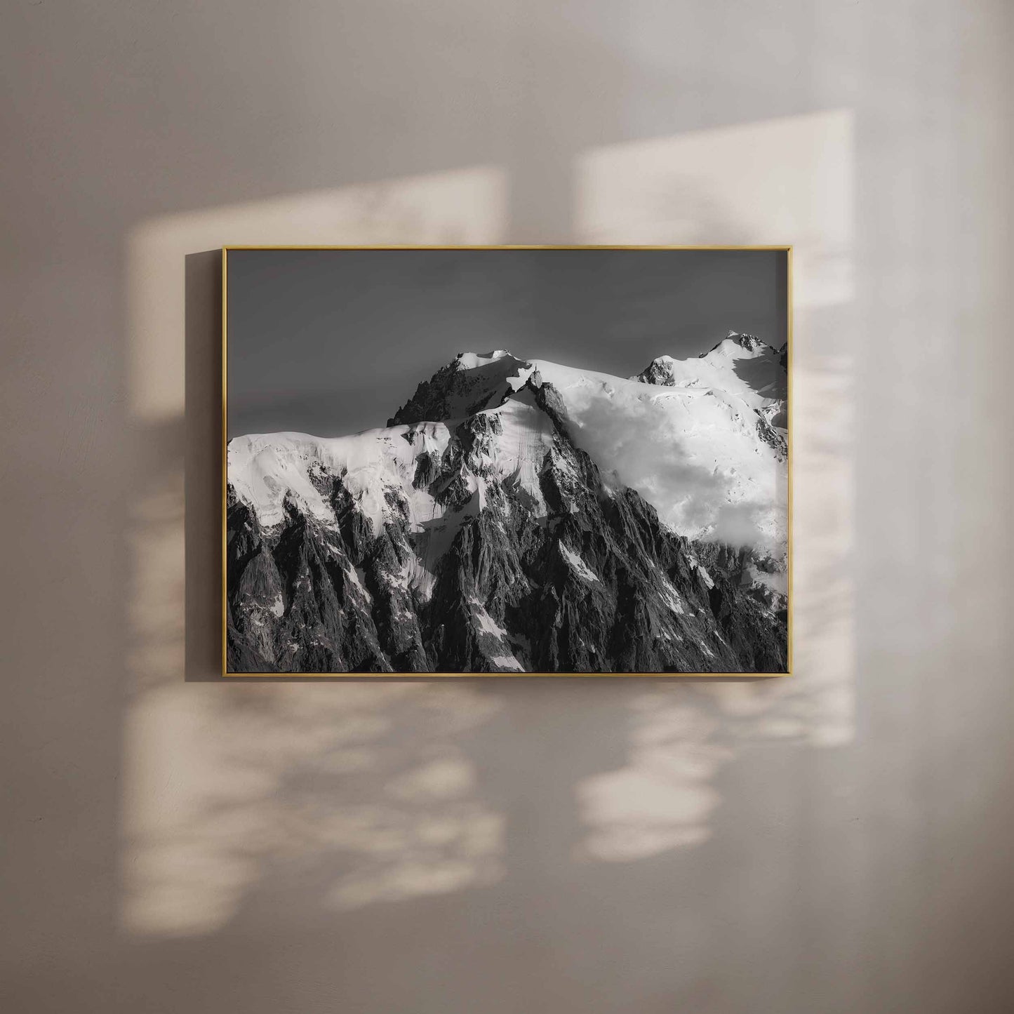 Black and white photograph of the Aiguille du Midi in Chamonix, displayed with soft wall shadows in a gold frame.