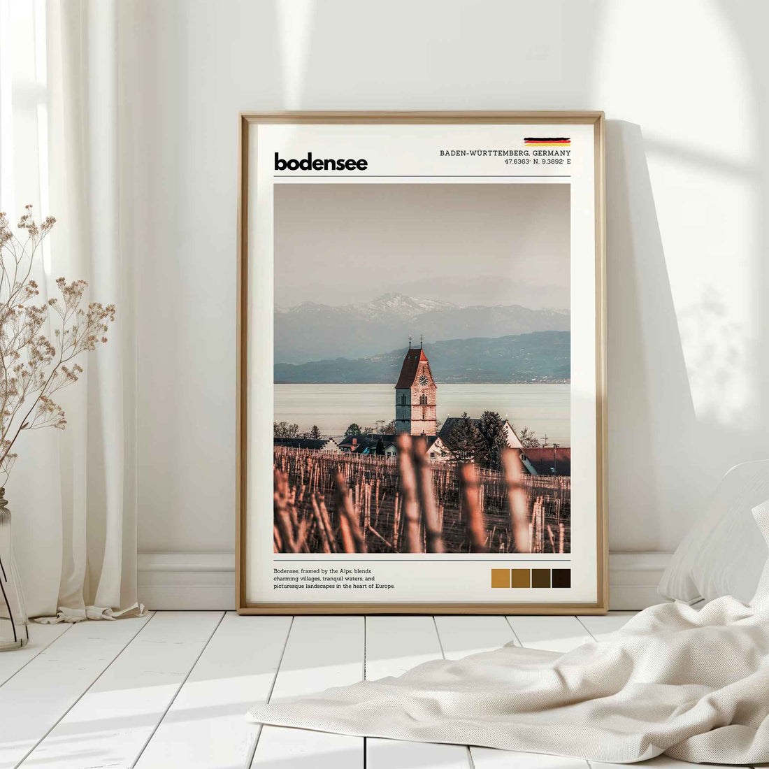 Natural wood framed Bodensee Lake Constance Germany church vineyard print leaning against white wall on white floorboards in minimal Scandinavian interior