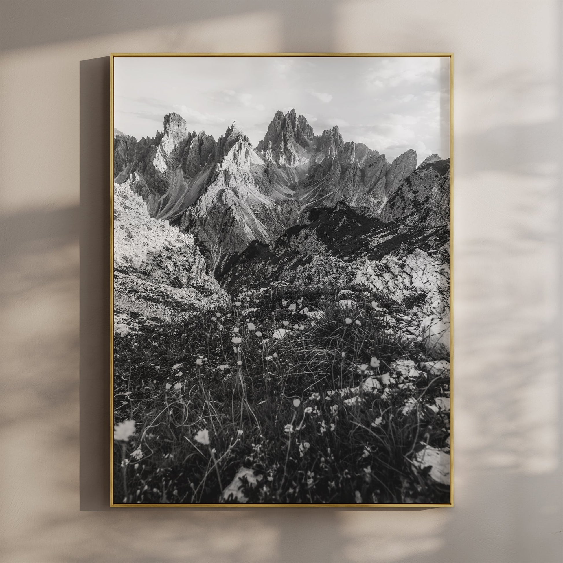 Black and white print of the Cadini di Misurina peaks hanging on a neutral wall in golden light.