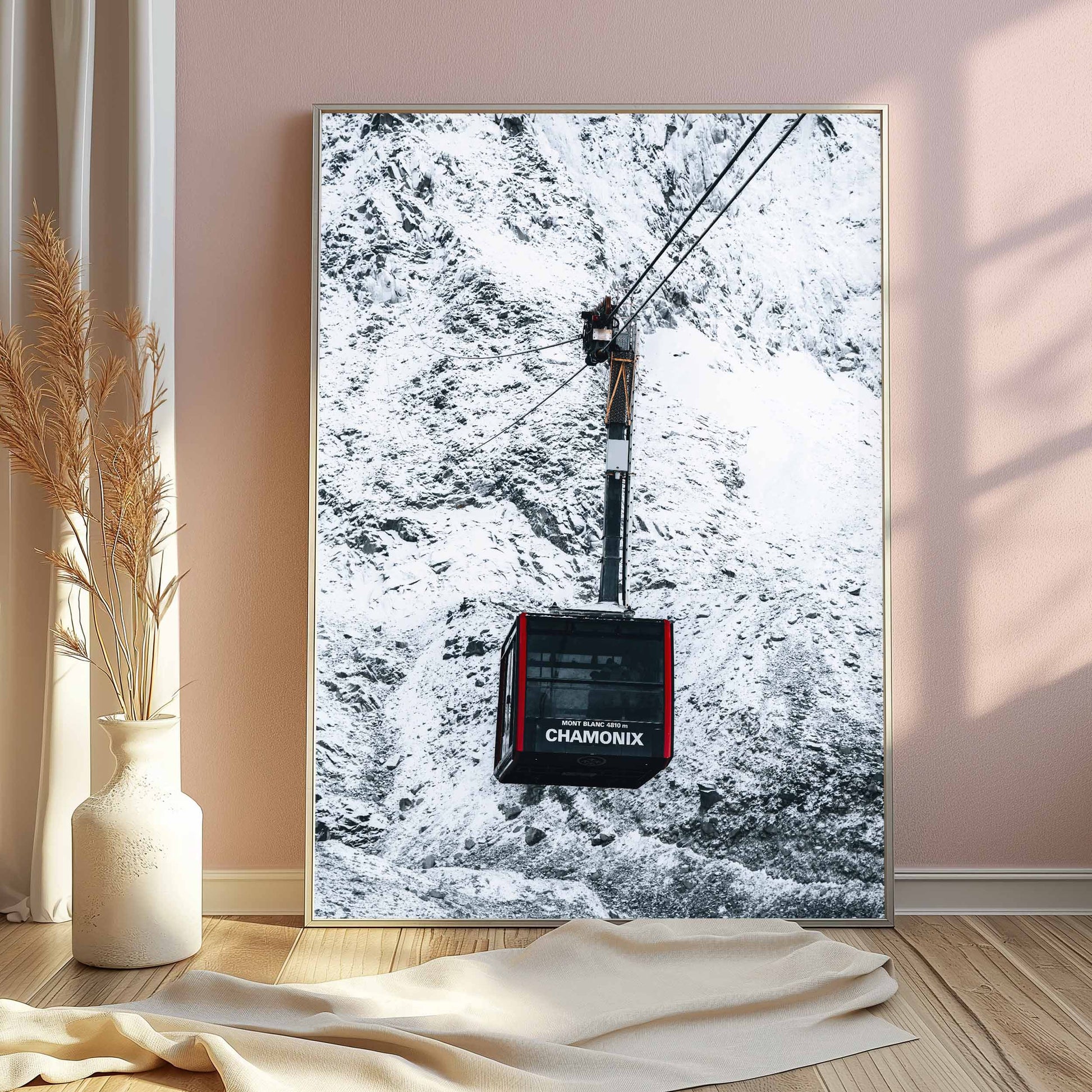 Chamonix cable car artwork in a silver frame, displayed in a soft pink-toned room with elegant decor.