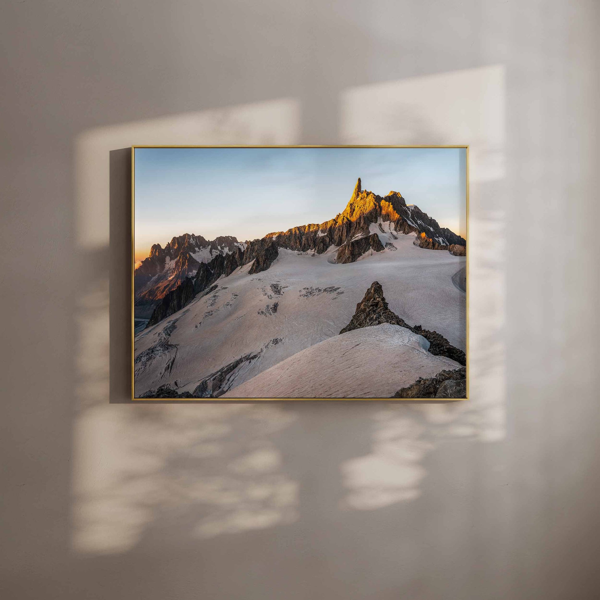 Wall art of the Dent du Géant illuminated by golden hour light, framed in a cozy interior.