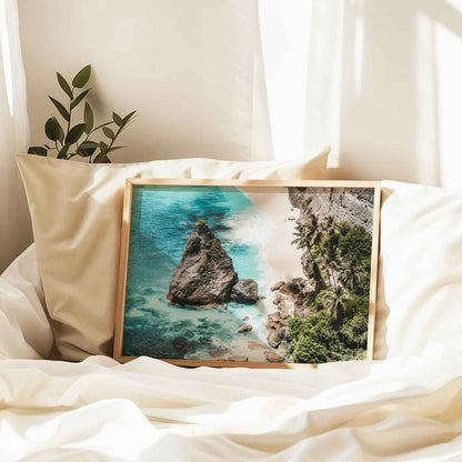 Diamond Beach Nusa Penida landscape framed print in natural wood frame leaning against pillow on white bed