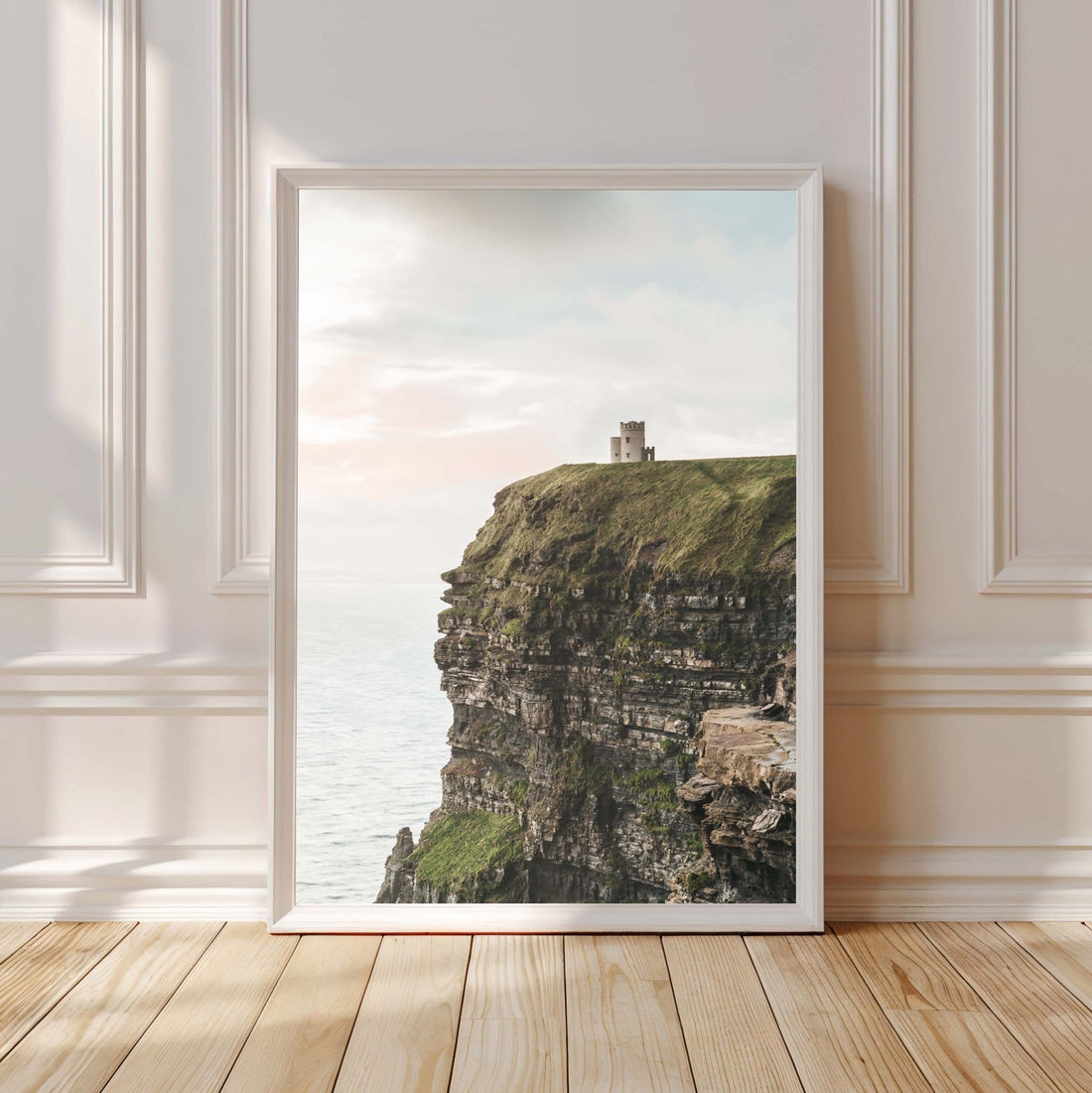 Cliffs of Moher unframed print displayed in white frame against a light interior wall with wooden floor, green and beige tones