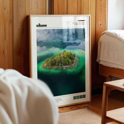 Framed Eibsee aerial island Bavaria Germany print in natural wood frame leaning against pine panelled bedroom wall