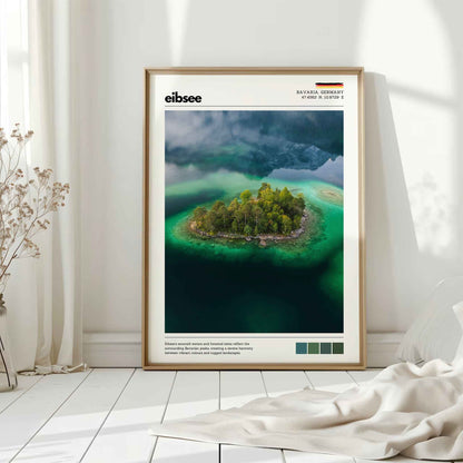 Natural wood framed Eibsee aerial island Bavaria Germany print leaning against white wall on white floorboards in minimal Scandinavian interior