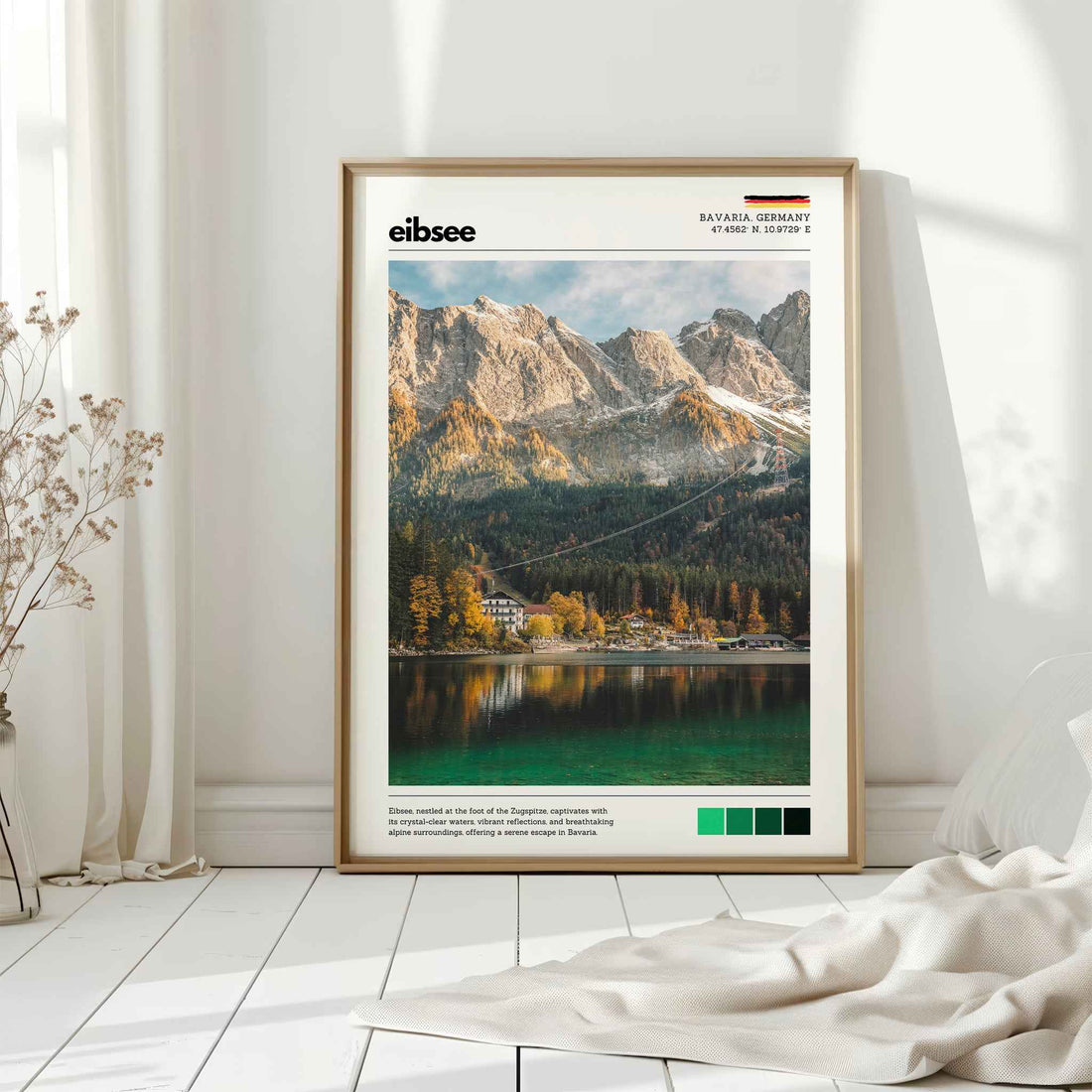 Natural wood framed Eibsee autumn Zugspitze Bavaria Germany print leaning against white wall on white floorboards in minimal Scandinavian interior