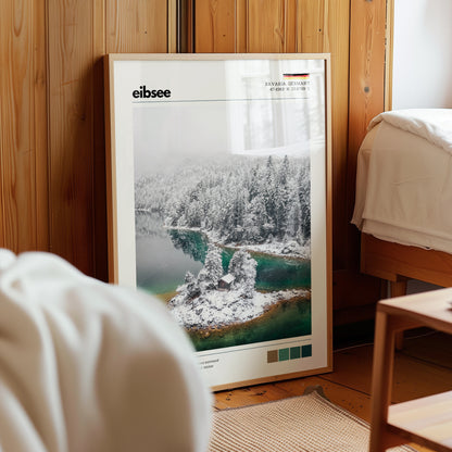 Framed Eibsee winter island cabin Bavaria Germany aerial print in natural wood frame leaning against pine panelled bedroom wall