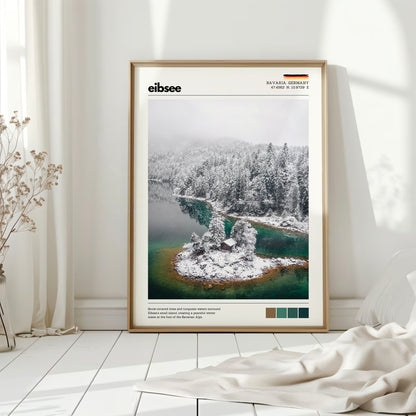 Natural wood framed Eibsee winter island cabin Bavaria Germany print leaning against white wall on white floorboards in minimal Scandinavian interior