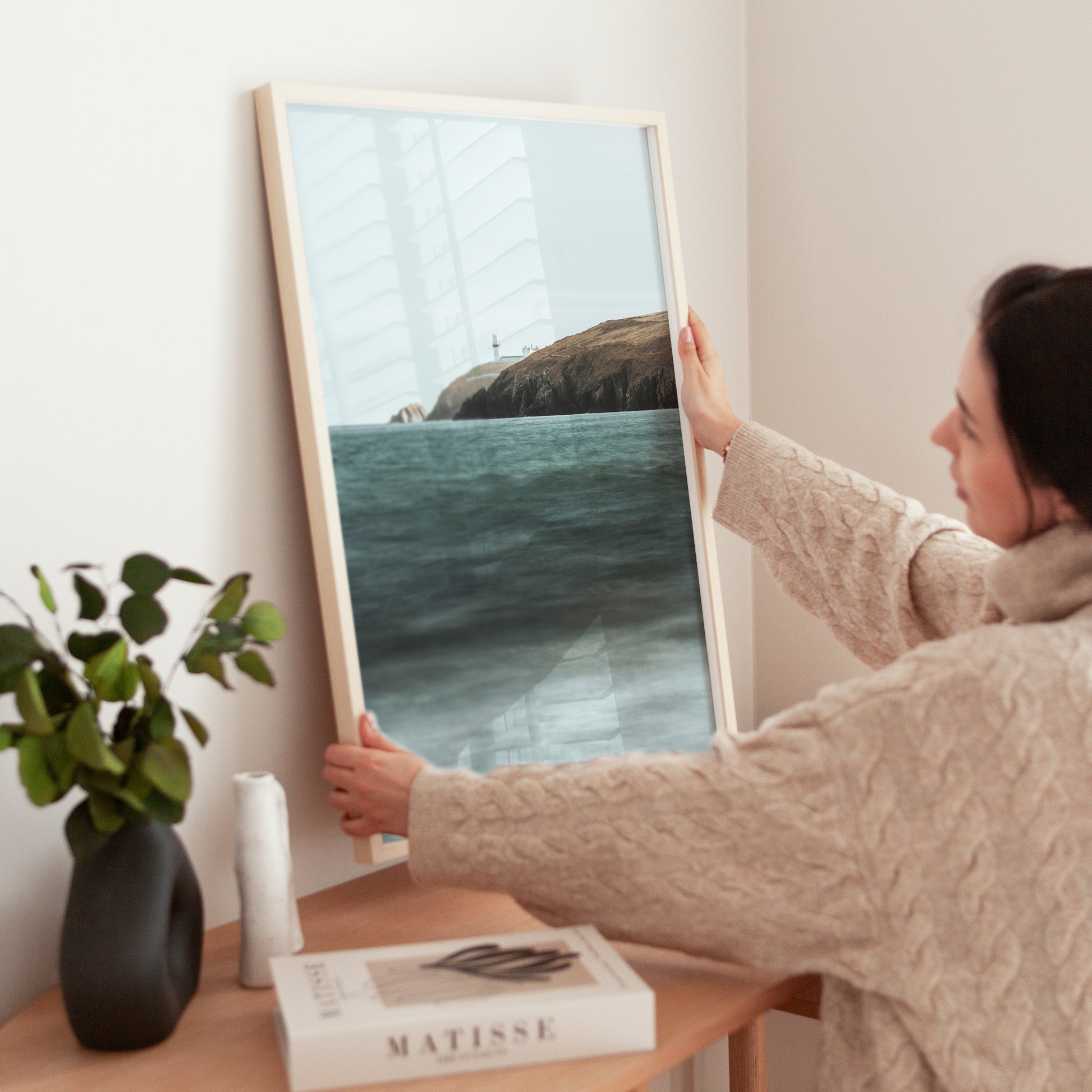 Woman placing Galley Head Lighthouse photo art on a tabletop in neutral decor