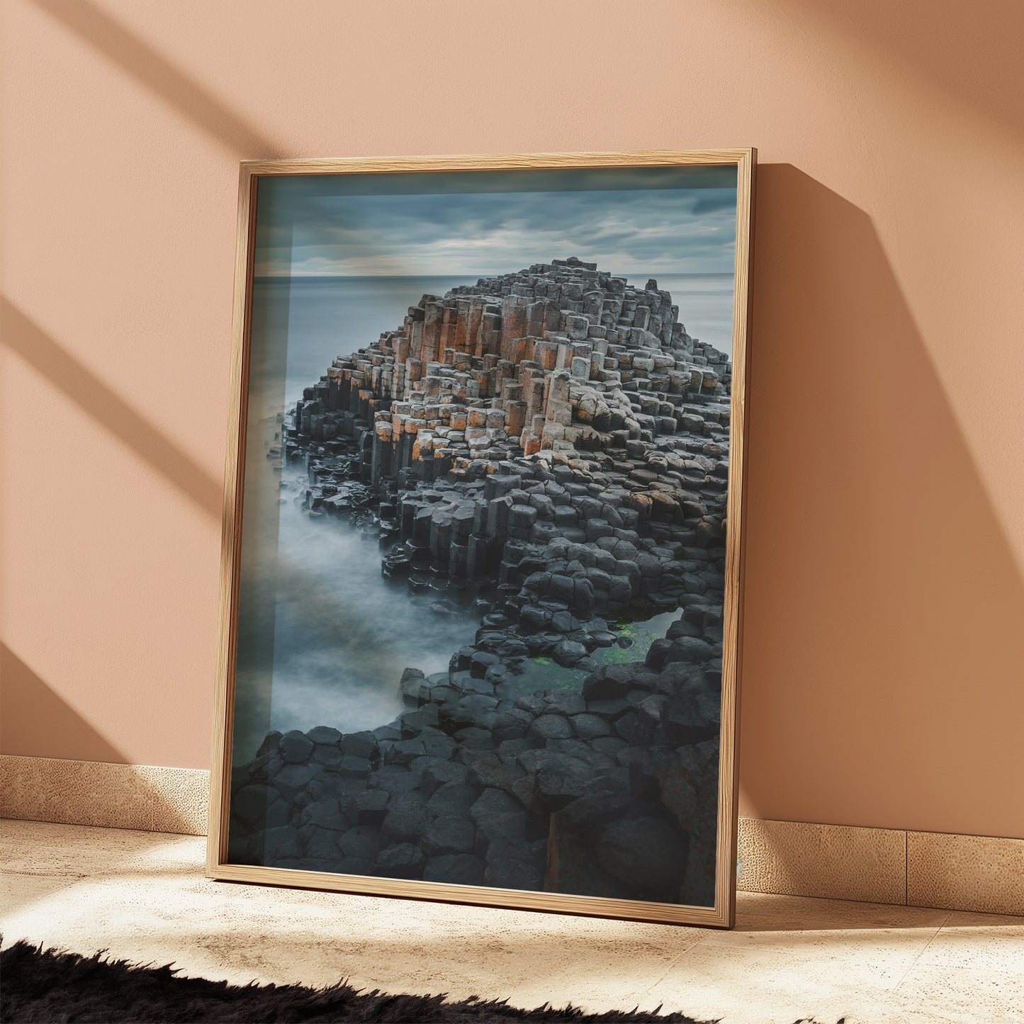 Framed Giant's Causeway seascape art leaning on a warm peach wall