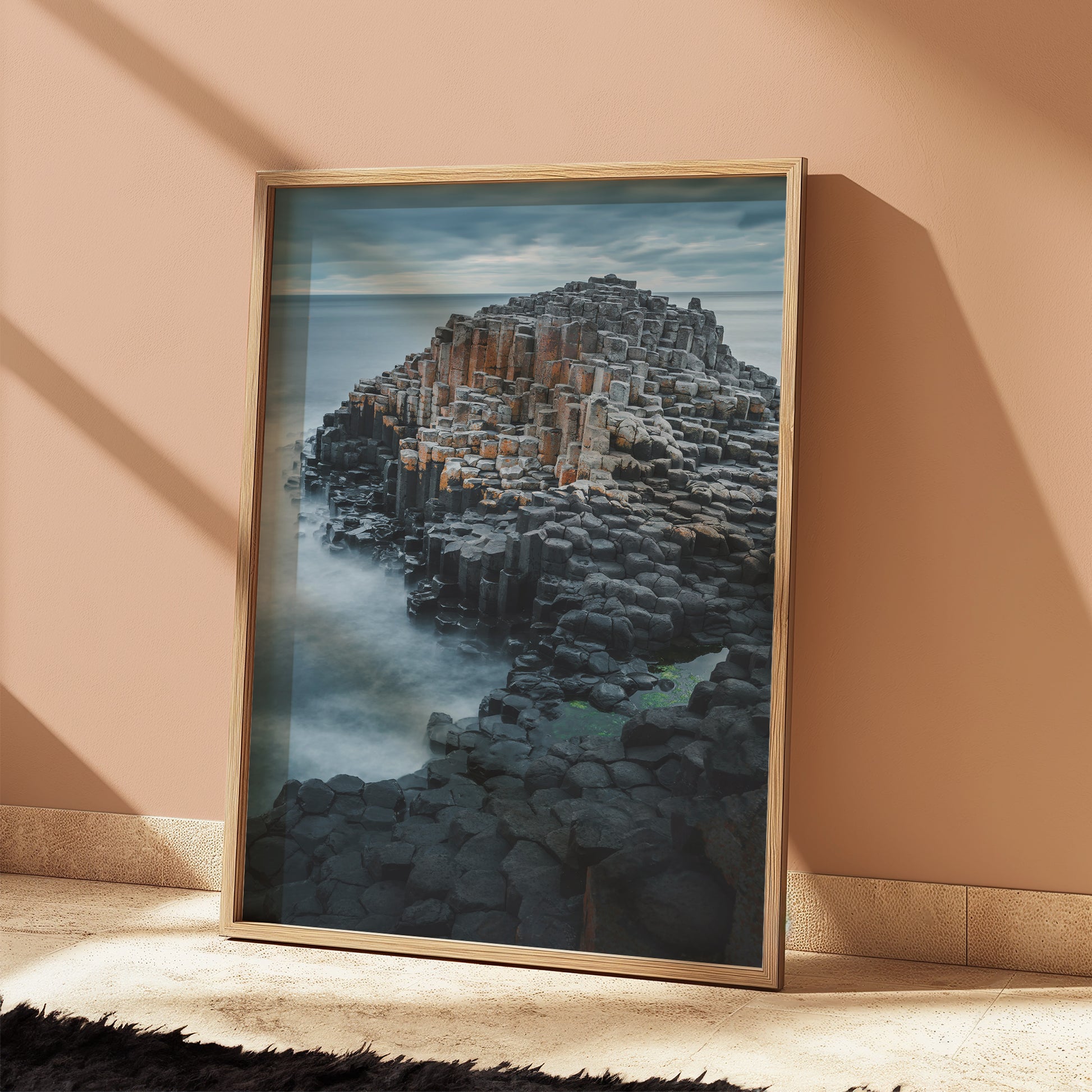 Framed Giant's Causeway seascape art leaning on a warm peach wall