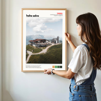 Person holding a Hohe Salve Austrian Alps location poster with alpine scenery and mountain architecture