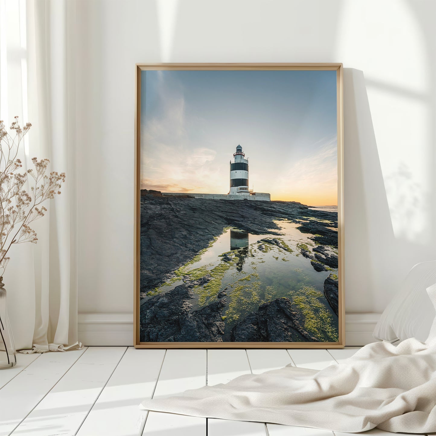 Framed Irish lighthouse print by a white wall with natural light and floor decor