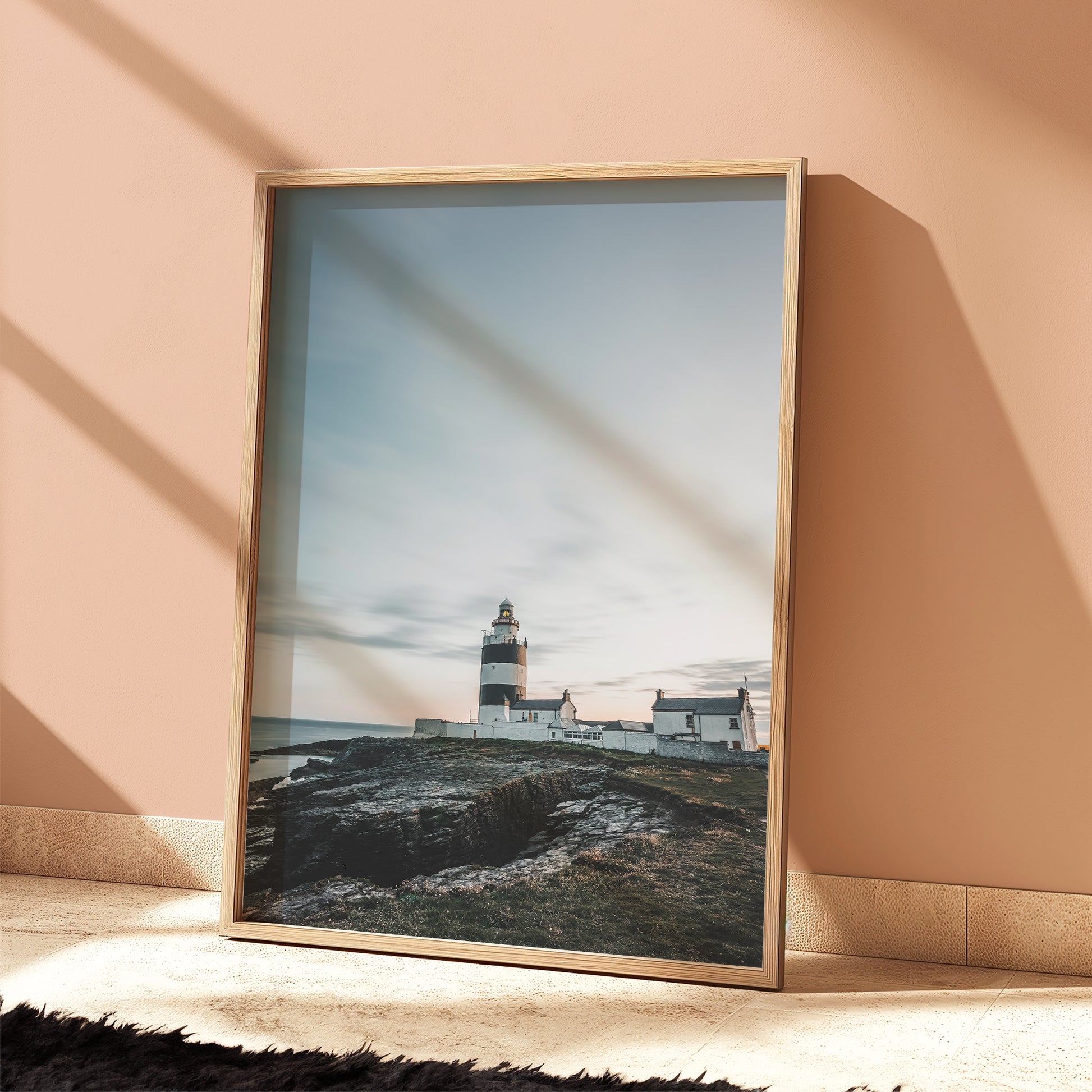 Coastal lighthouse framed print styled in terracotta room with soft shadows