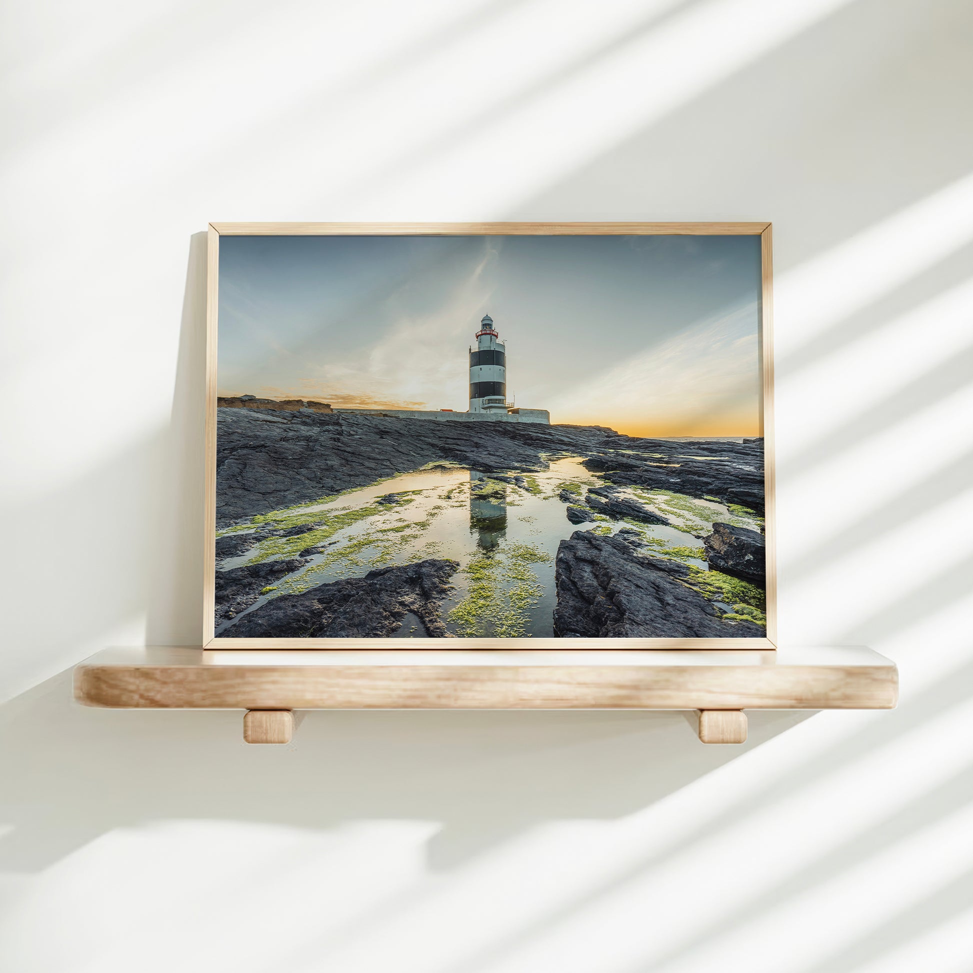 Aerial view of Hook Head Lighthouse at sunset with soft golden sky.