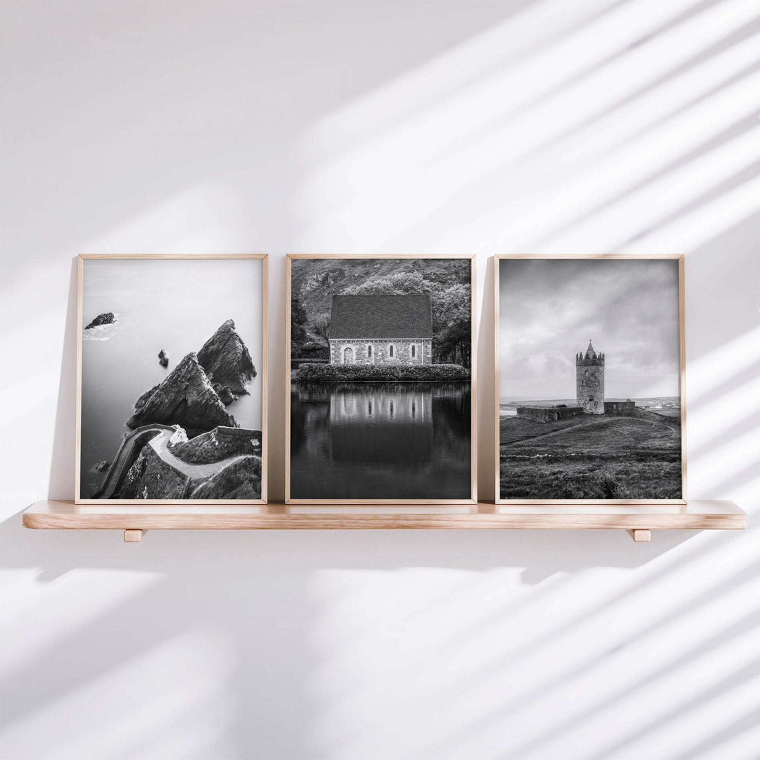 Black and white Irish wall art set of three framed prints displayed on a white shelf with soft natural light and shadows.