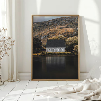 Framed print of Gougane Barra chapel in bright, natural-lit bedroom setting
