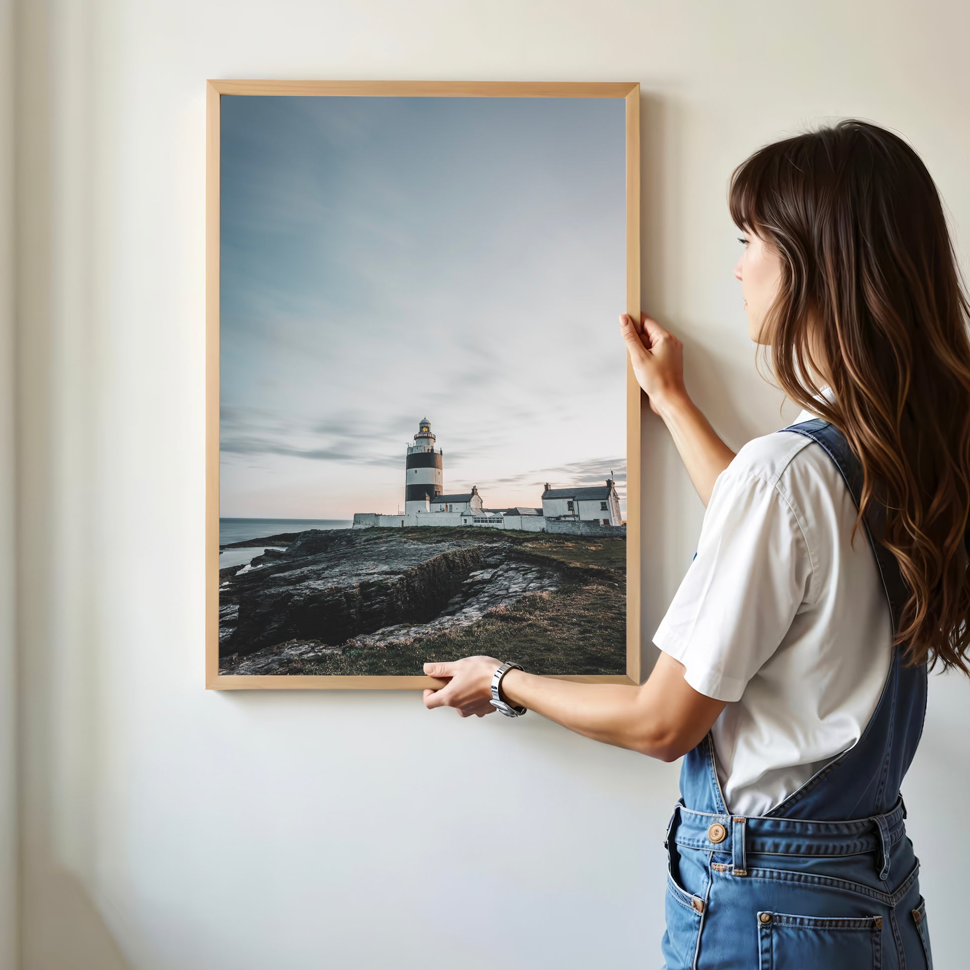 Woman hanging Hook Head Lighthouse print on white wall, natural light